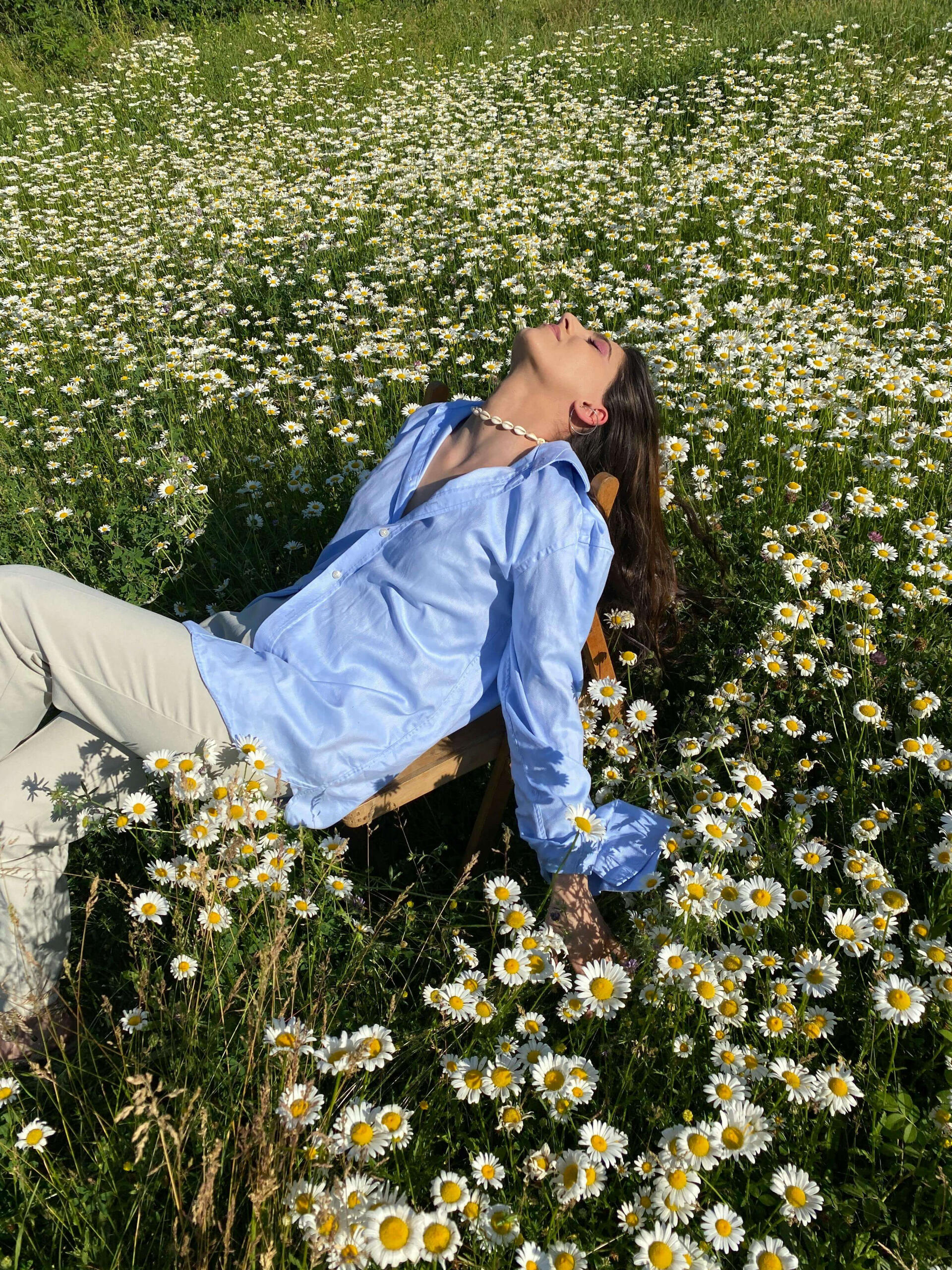 Feminine flow This is a photo of a woman lying back on a chair in a field of white daisies