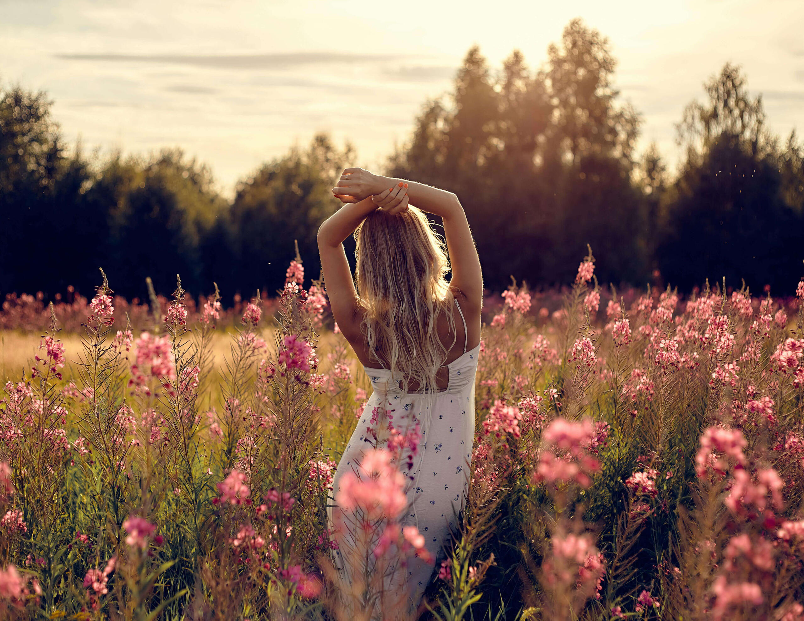 The Flow Frequency This is a photo of a woman standing in a field of pink flowers feeling free